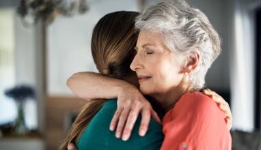 
		Older woman hugs a young woman intimately
	